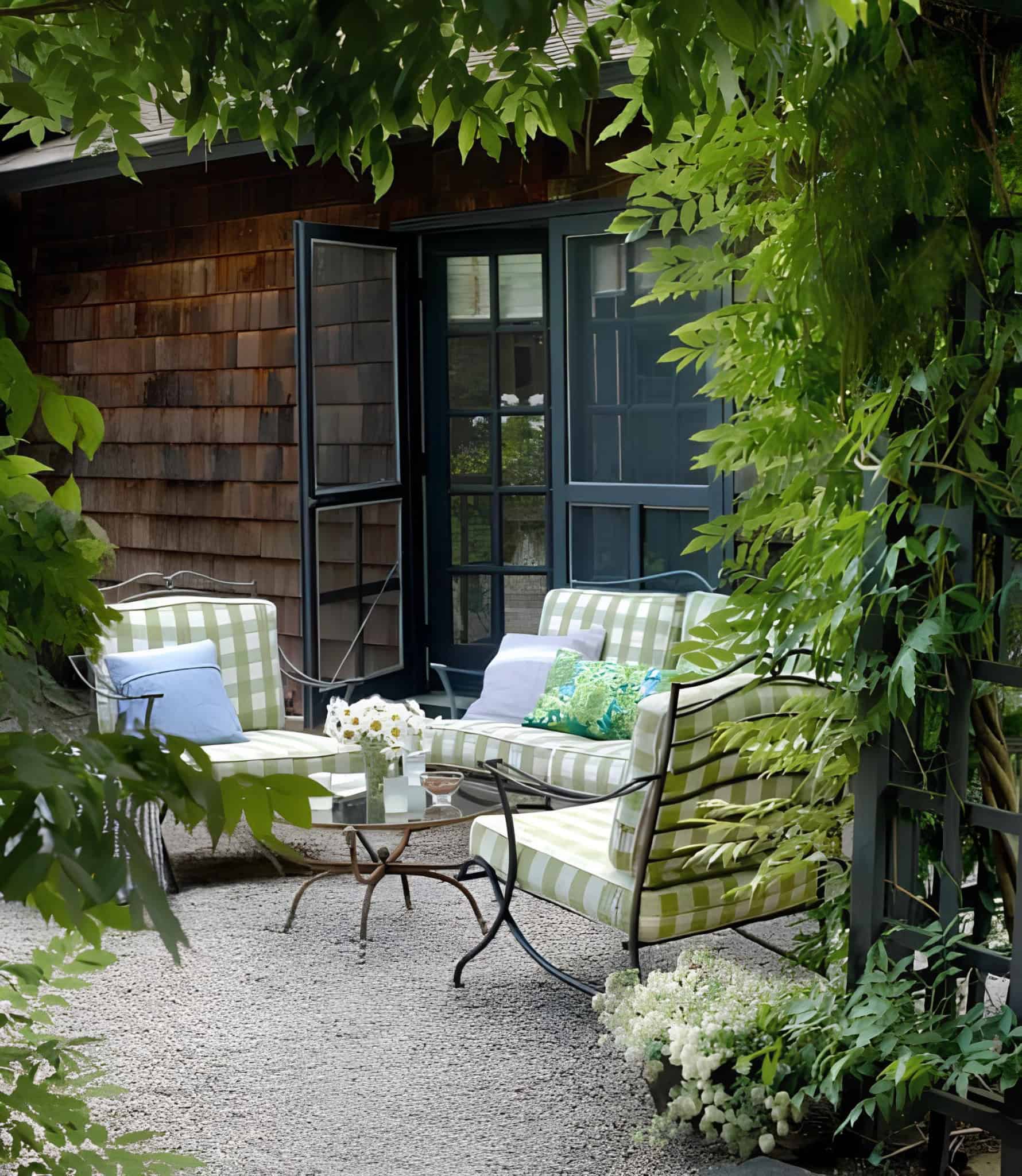 Stylish garden seating area with green plaid cushions and glass table