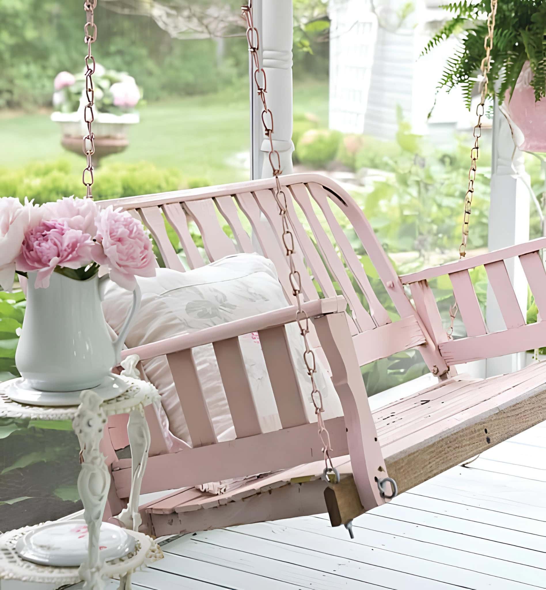 Blush pink porch swing with floral cushion and pitcher of flowers