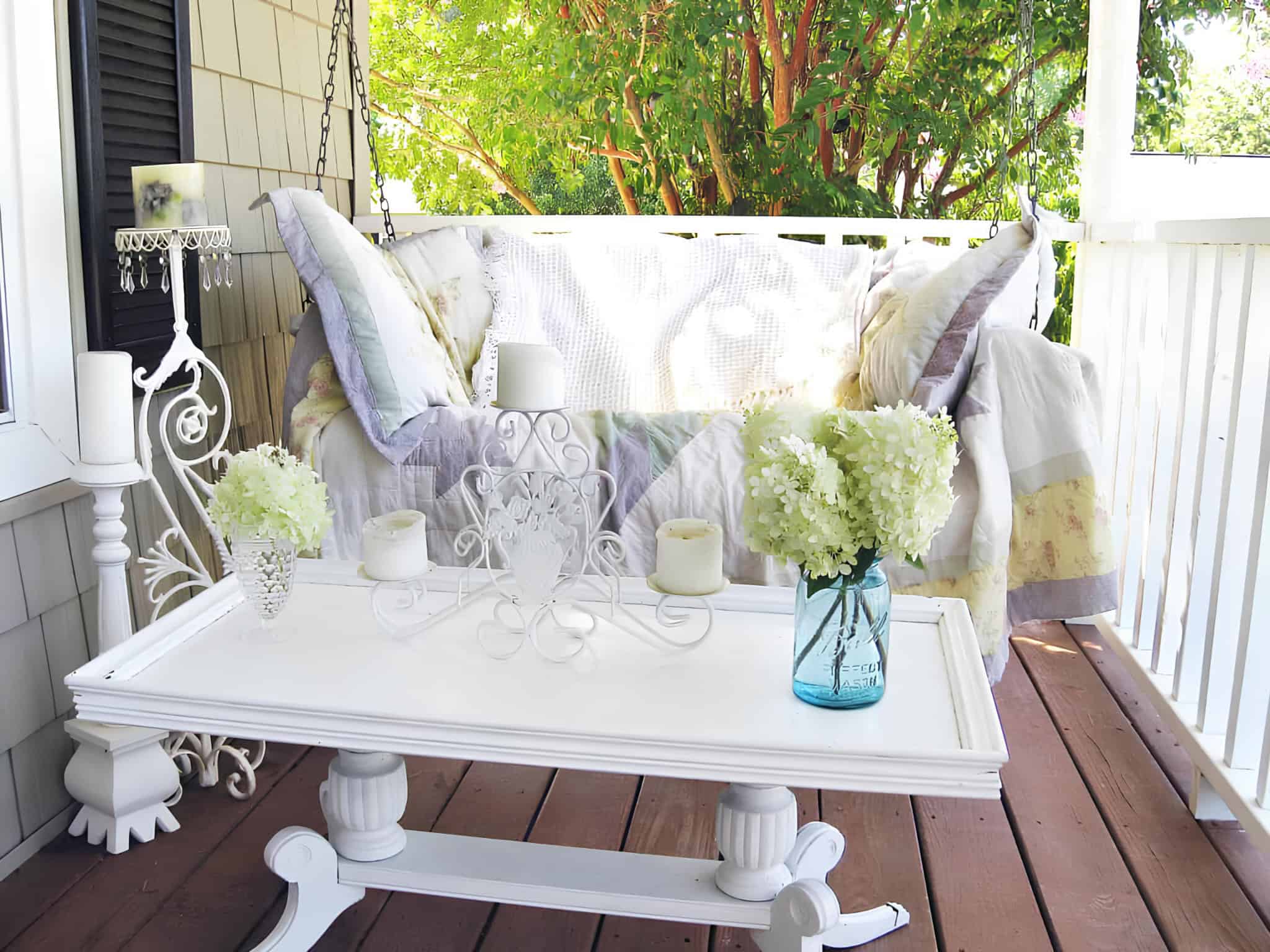 White porch swing and hydrangea centerpiece on wooden deck