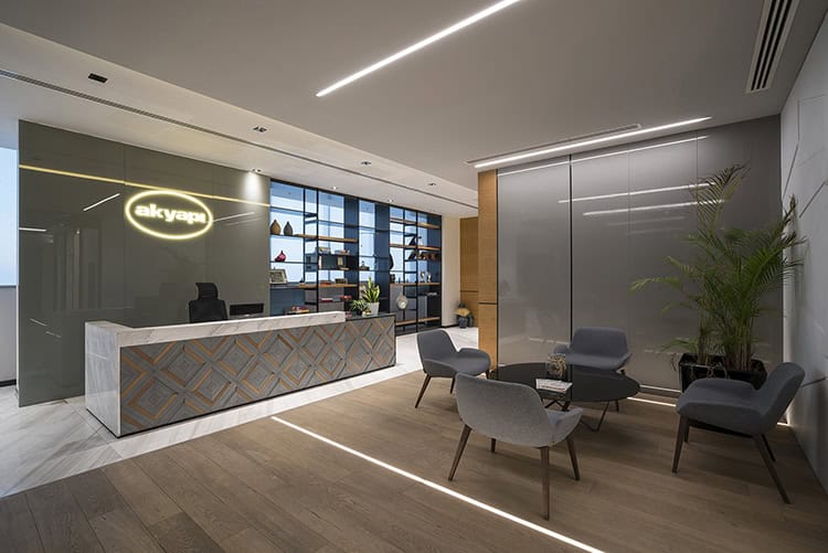 Modern office reception area with sleek design, stylish seating, and contemporary decor, featuring minimalist lighting and decorative shelves for an inviting workspace atmosphere.
