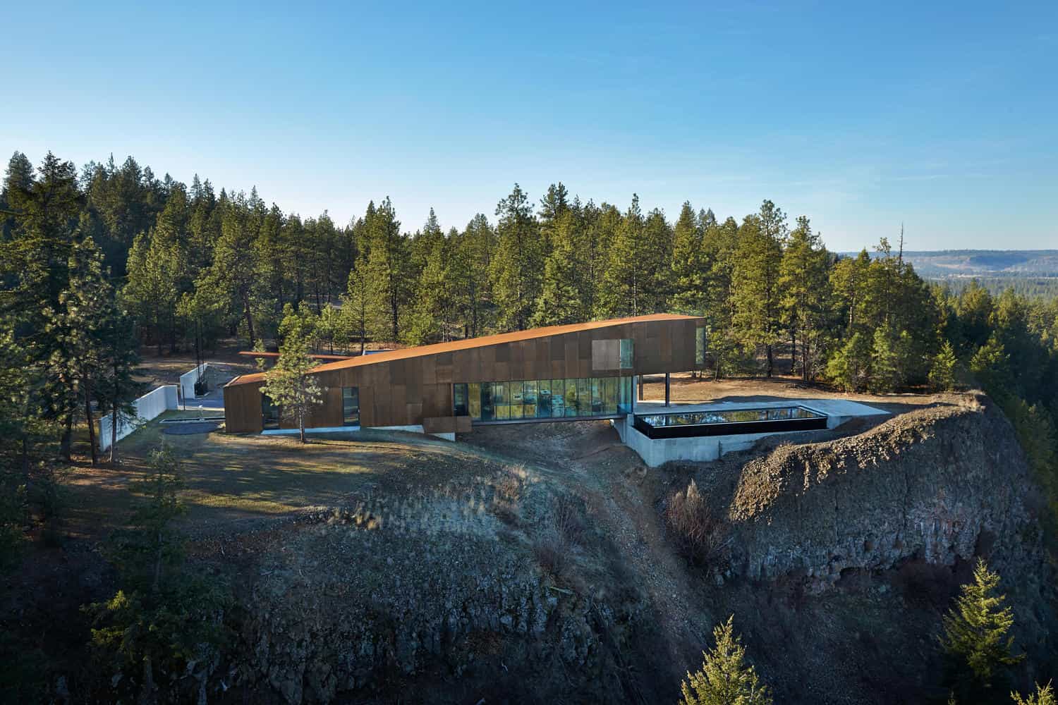 Contemporary modern house nestled in a forested landscape with large glass windows and unique angular roof design, blending architecture art with natural surroundings.