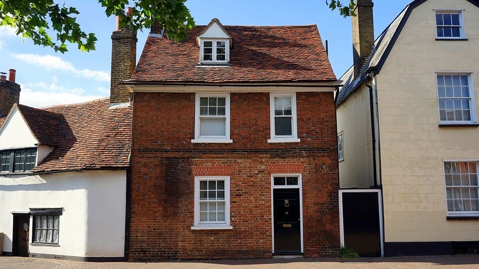 Traditional red brick terraced house with white-framed windows and a black front door in a charming neighborhood.