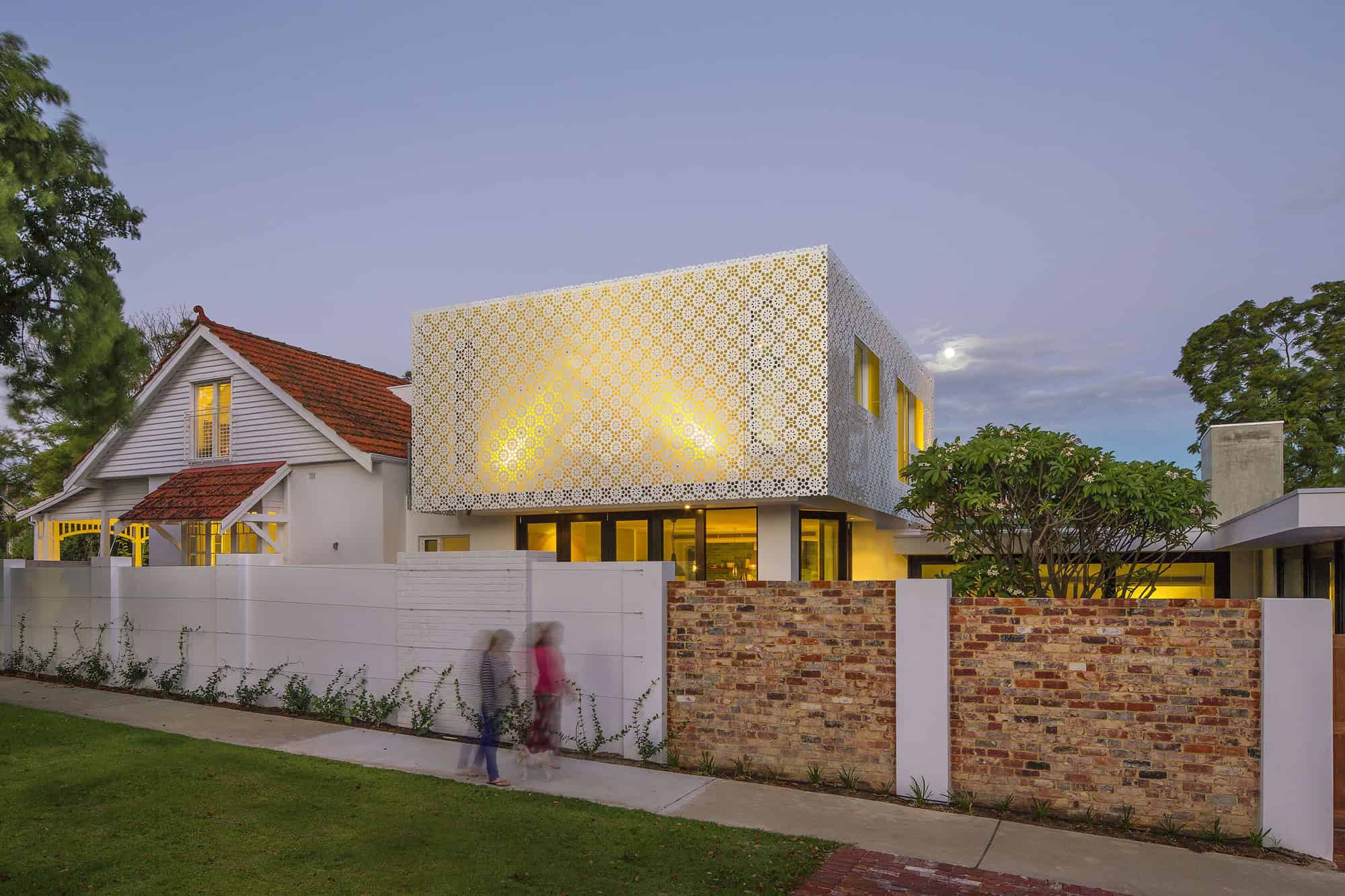 Contemporary modern house with unique perforated facade, large glass windows, and a blend of traditional and modern architectural styles. Elegant exterior design with creative use of materials and lighting.