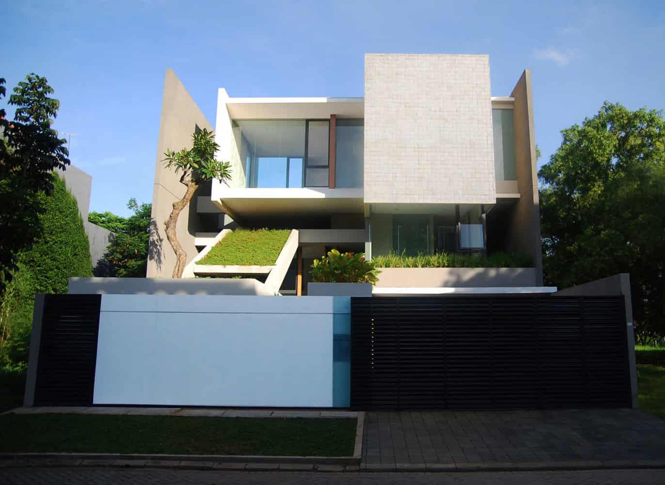 Modern minimalist house with clean lines and geometric design, featuring large glass windows, lush landscaping, and contemporary architecture elements.