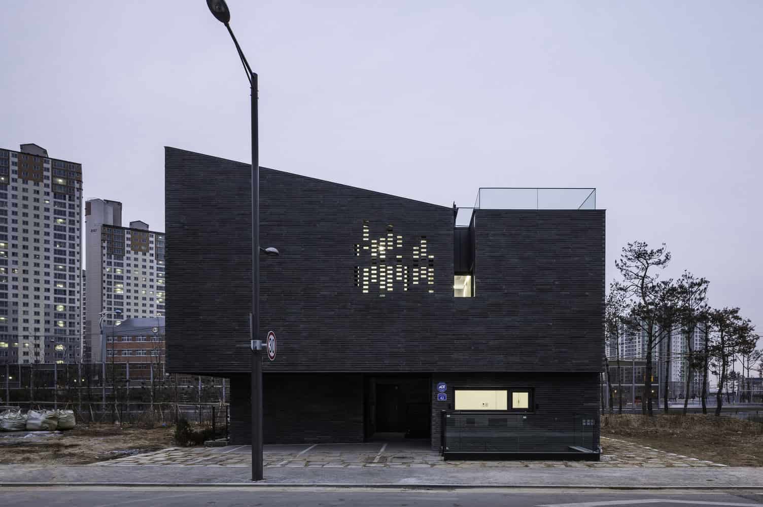 Contemporary modern black brick residential building with unique perforated design element, urban setting, creative architecture, cityscape, minimalist style.