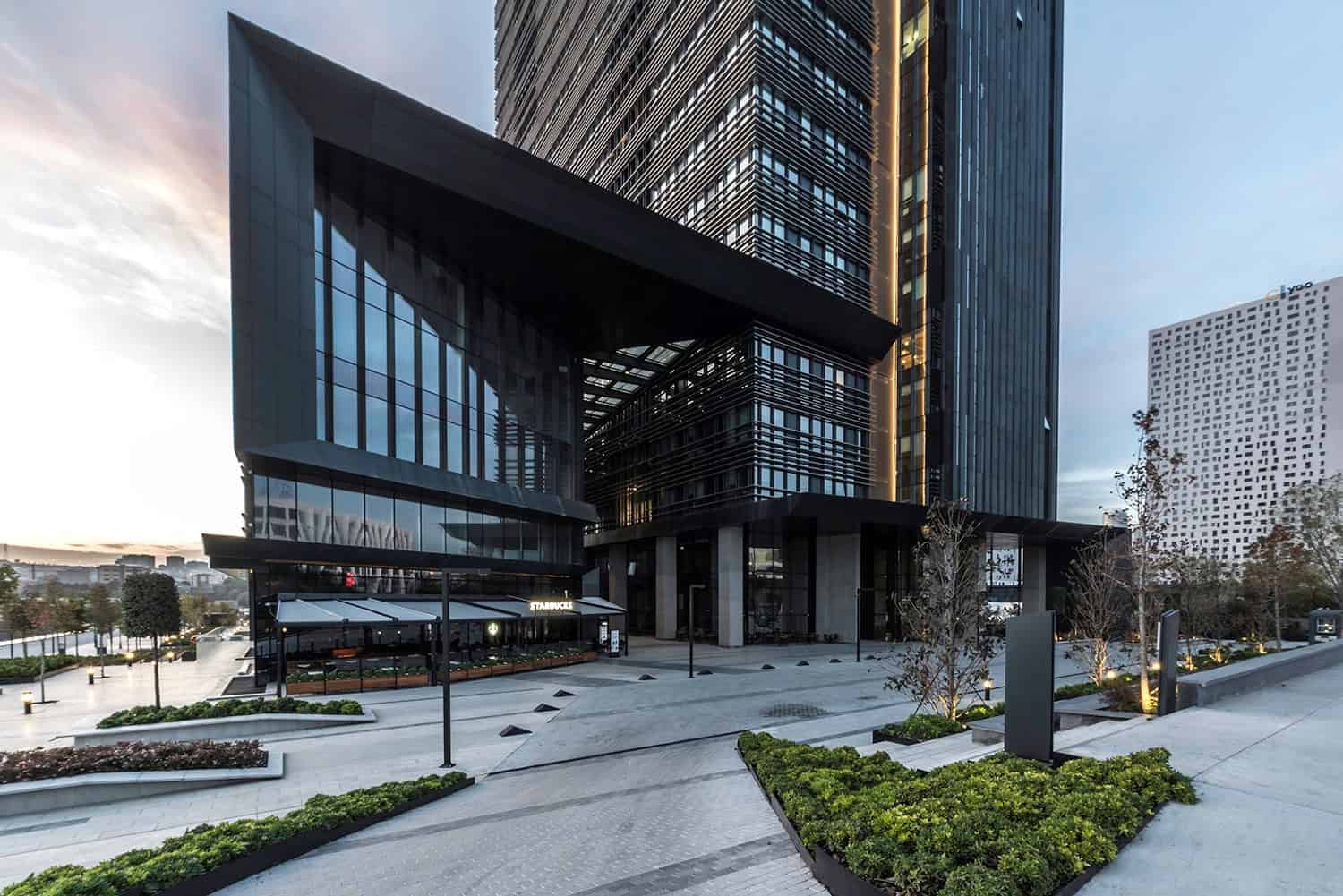 Contemporary high-rise building with modern architecture, glass facades, and sleek design featuring urban landscape and landscaped grounds.