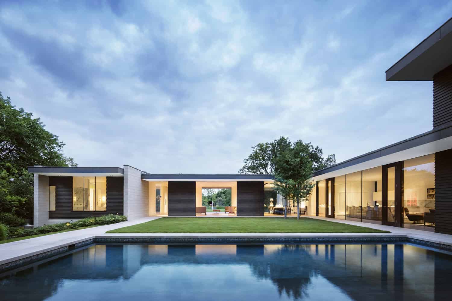 Contemporary modern house with open floor plan, large glass windows, and a backyard pool, showcasing sleek architectural design and outdoor living space.