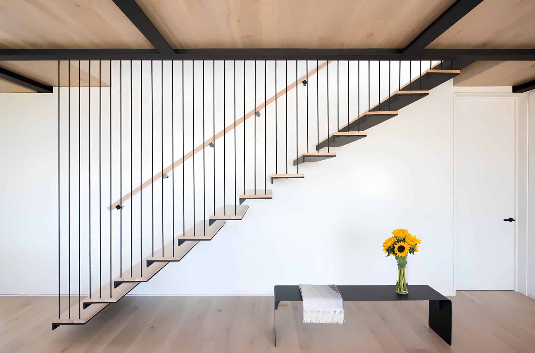 Atlantic House Floating Staircase Metal Rail Floating staircase with black vertical metal railing in modern interior.