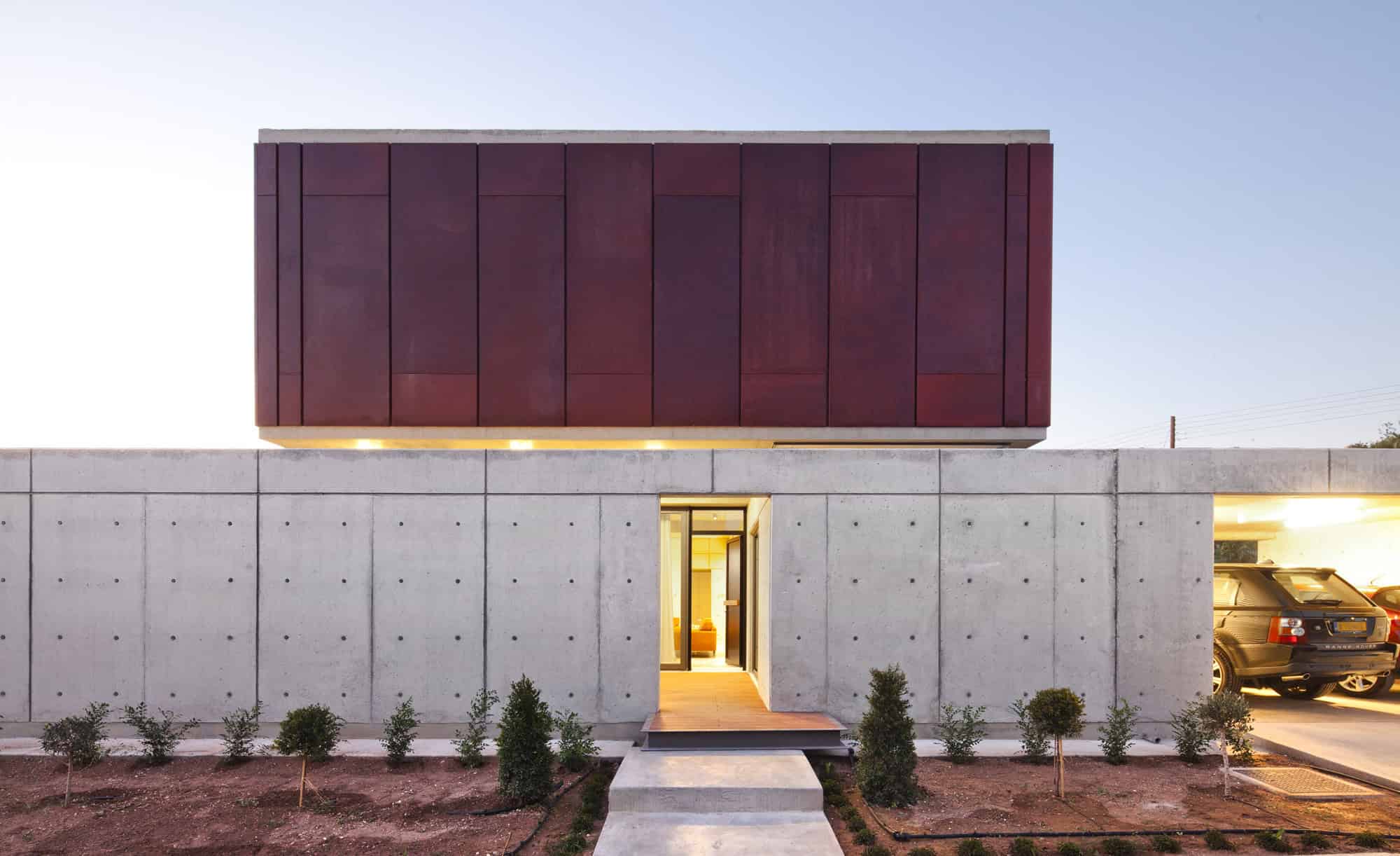 Modern concrete house with striking red cladding on the upper level, minimalist design, innovative architectural style, contemporary home exterior, sleek urban residential architecture.