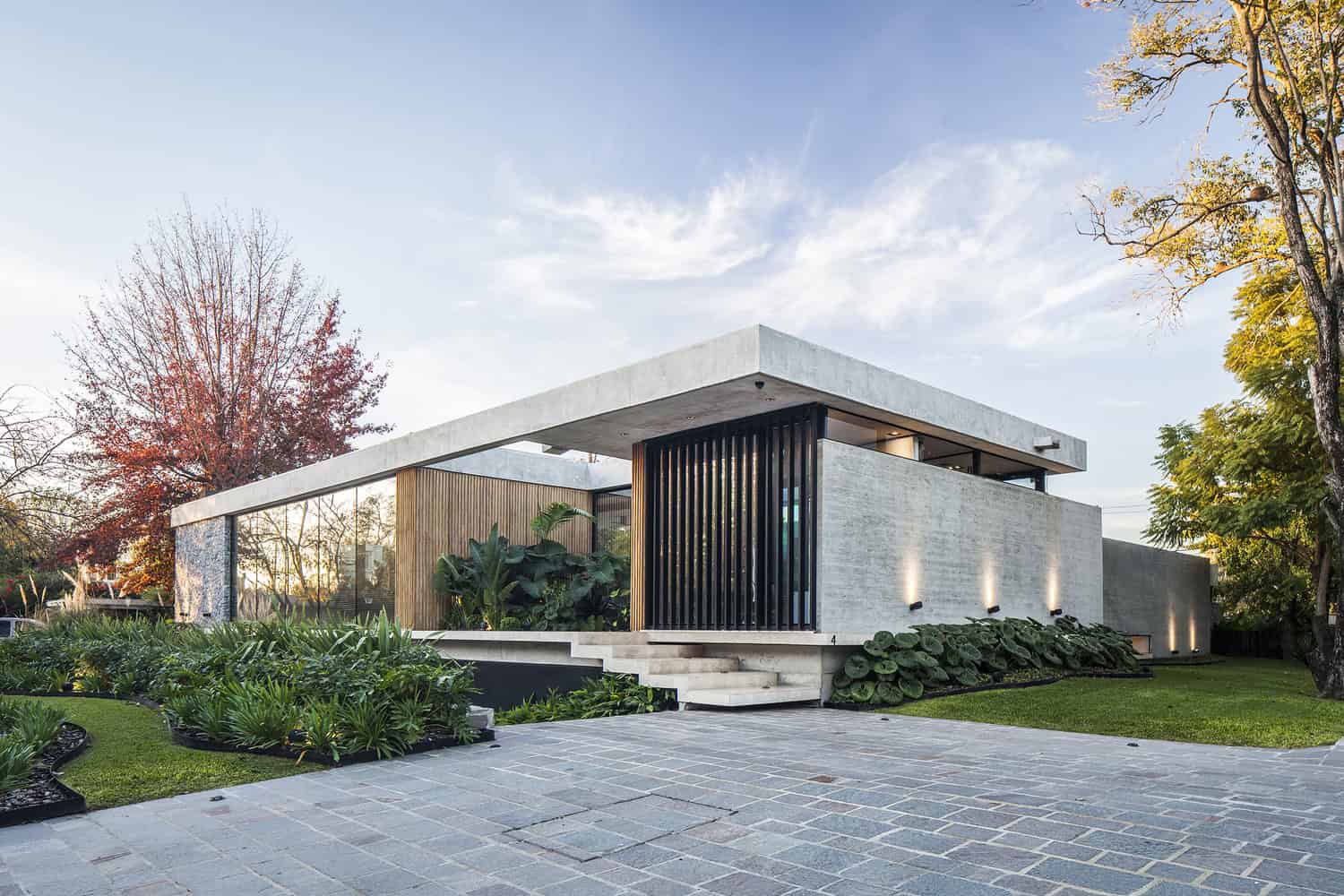 Contemporary modern house with minimalist architecture, flat roof, concrete and wood facade, large windows, and lush landscaping. Ideal for modern home design and outdoor living.