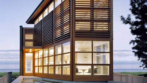 Contemporary modern house with wooden exterior and large glass windows, showcasing eco-friendly architectural design and sustainable materials.