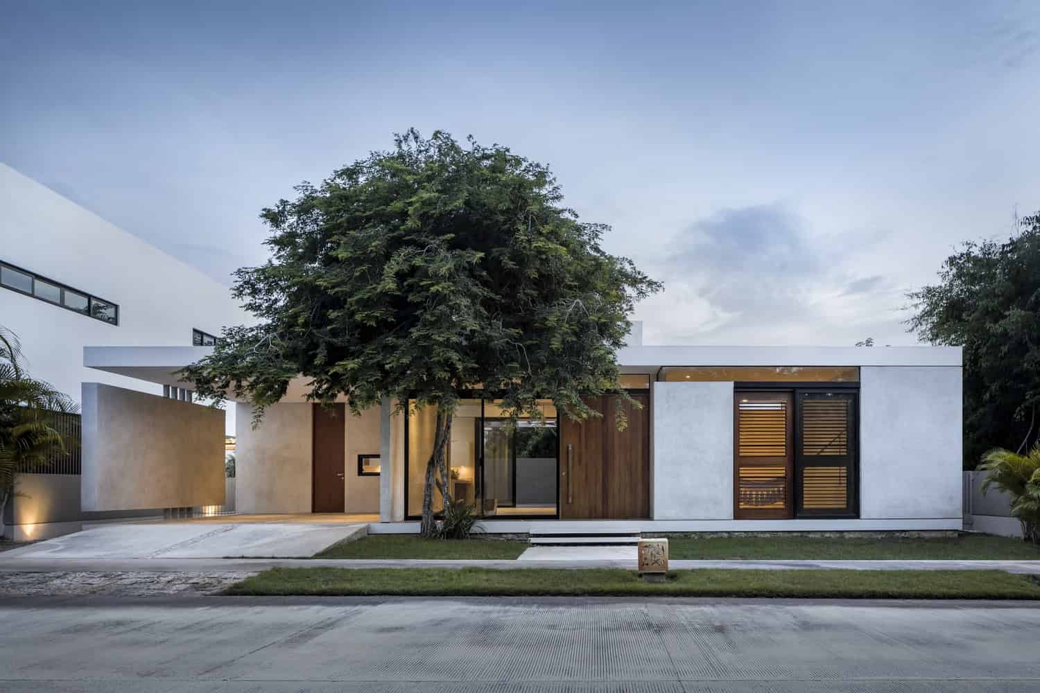 Sleek modern house with minimalist architecture featuring clean lines, large glass windows, and natural materials in a tranquil suburban setting.