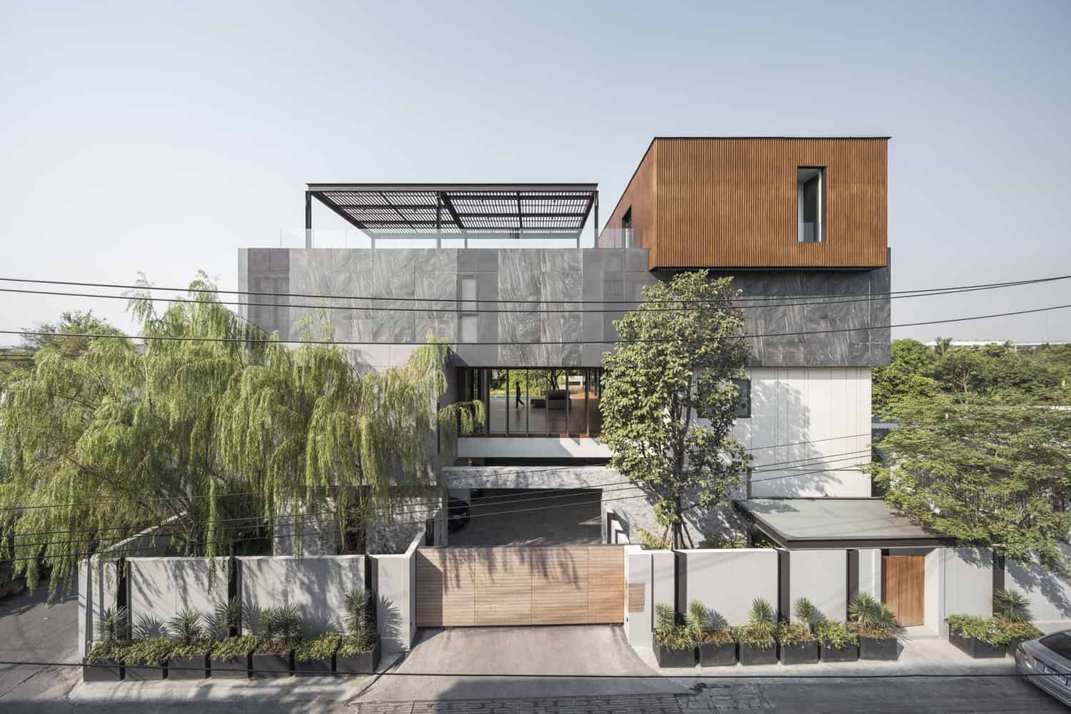 Contemporary modern house with sleek design, featuring concrete, wood, and glass elements, surrounded by greenery and urban landscaping.