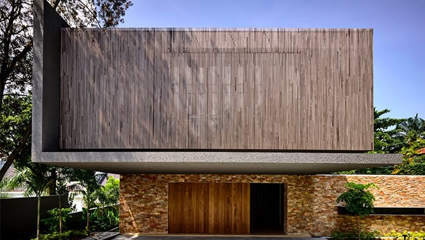 Sleek modern house facade with wooden cladding and stone accents, showcasing contemporary architecture and innovative design elements.