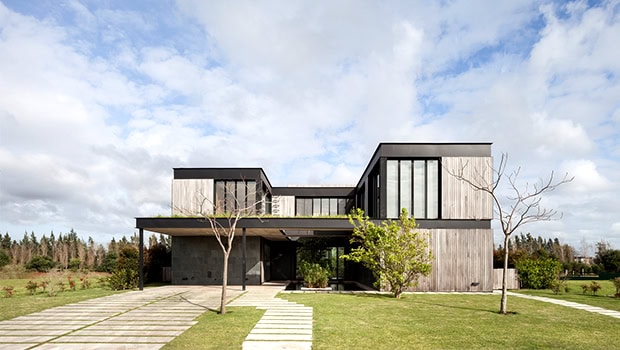 Sleek modern architectural house with minimalist design and large glass windows, surrounded by a well-manicured lawn and landscaped garden, showcasing contemporary architecture and artful design.