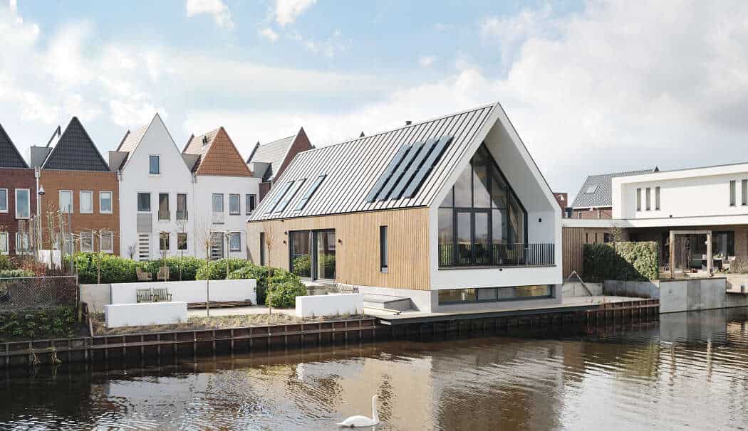 Contemporary house by a water canal featuring modern architecture, large glass windows, and sleek design, perfect for waterfront living and innovative architectural styles.