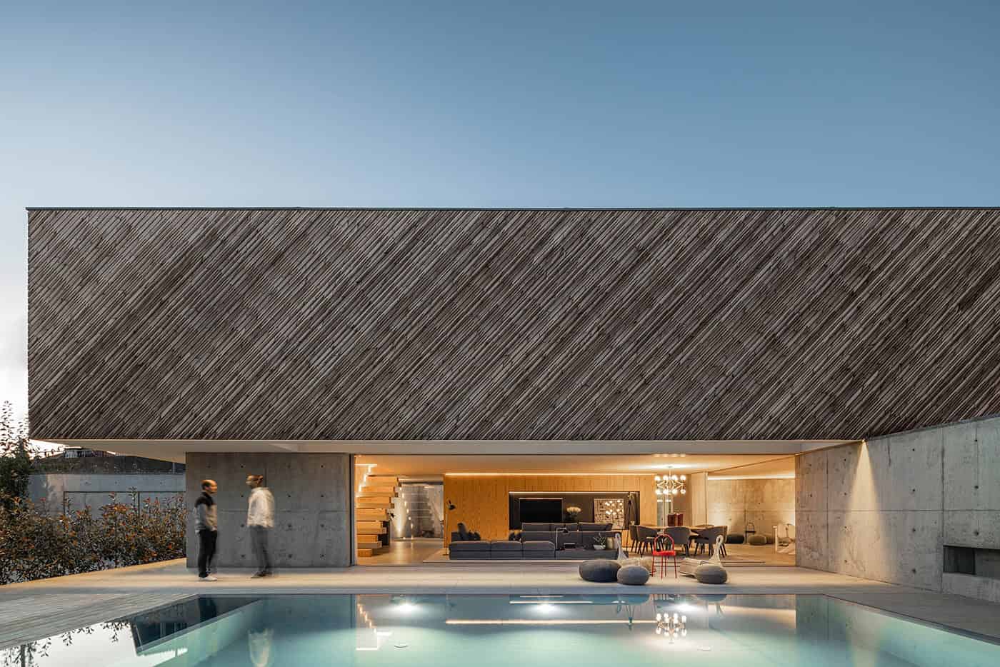 Contemporary modern house with a sleek design, wooden exterior, and open outdoor living space featuring a swimming pool and minimalist furniture, perfect for luxury architecture and innovative home designs.