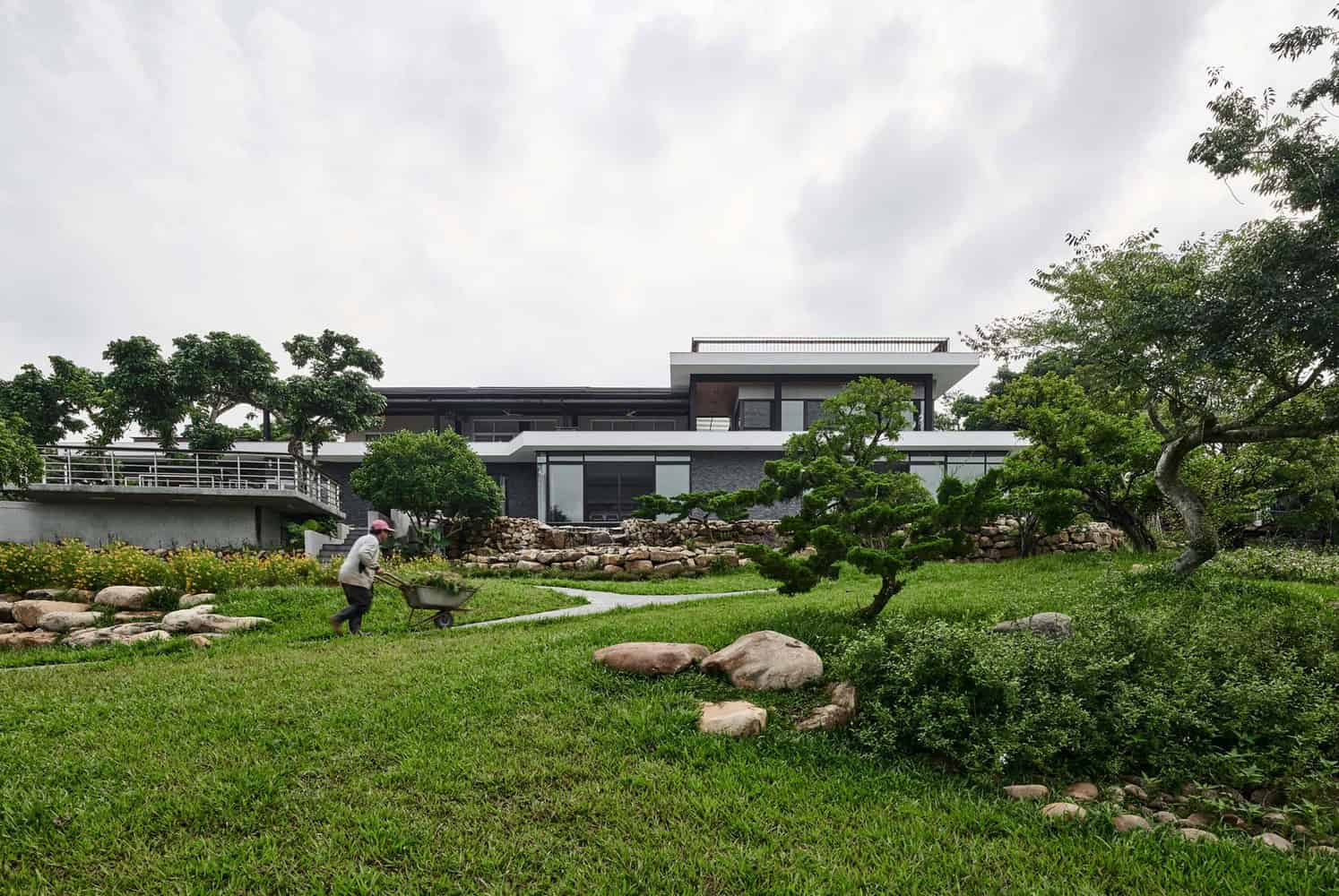 Modern contemporary house with sleek lines and large glass windows surrounded by lush greenery and landscaped garden.