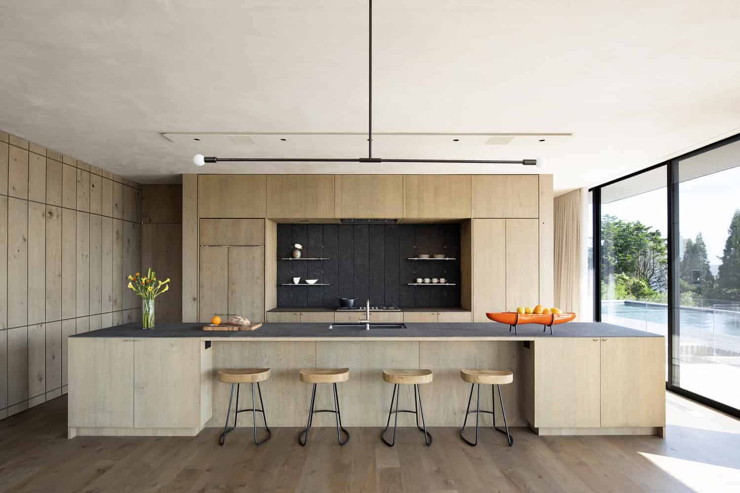 Kiht’han House Open Plan Kitchen Wood Paneling Open-plan kitchen featuring wood paneling and black central backsplash in Kiht’han House.