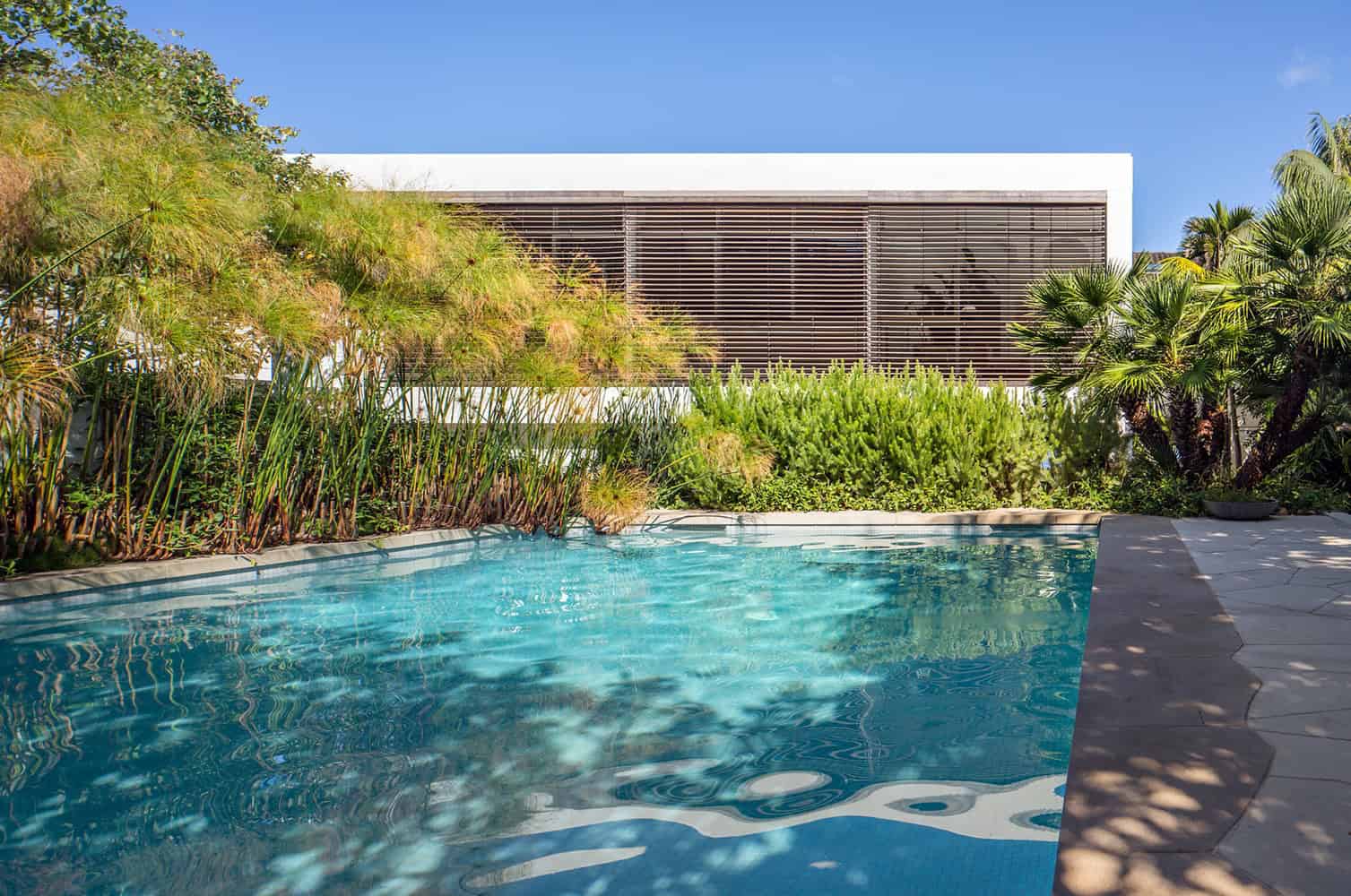 Contemporary modern house with a sleek design and lush tropical landscaping, featuring a private pool, perfect for luxury residential architecture and outdoor living spaces.