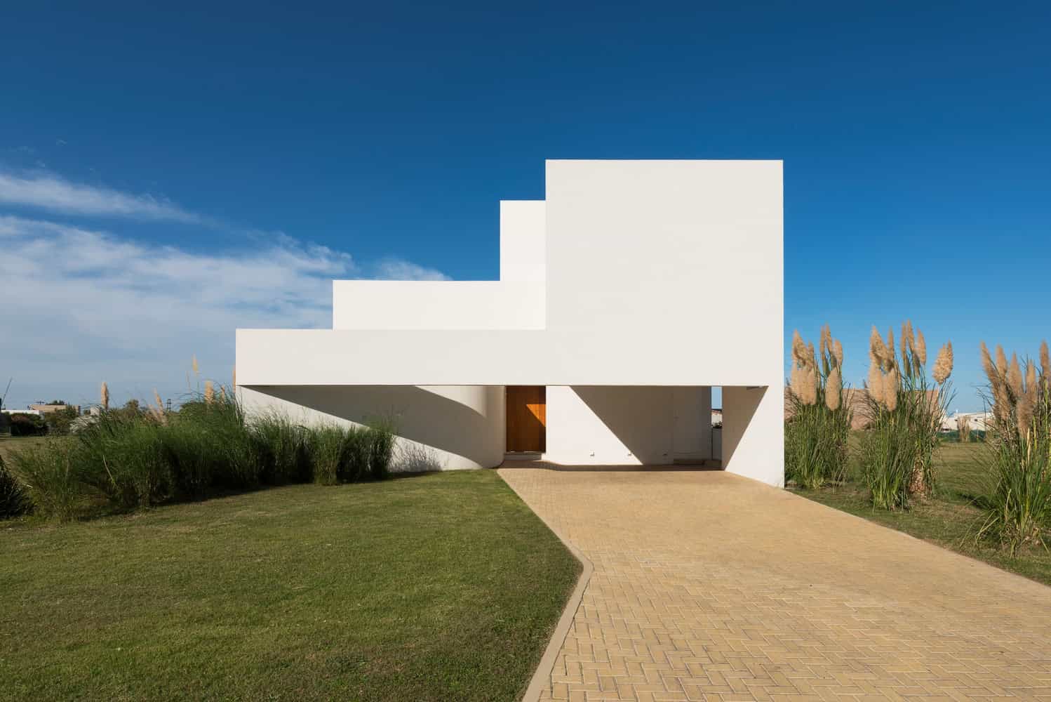 Contemporary white minimalist house with geometric designs and clean lines set in a landscaped garden.