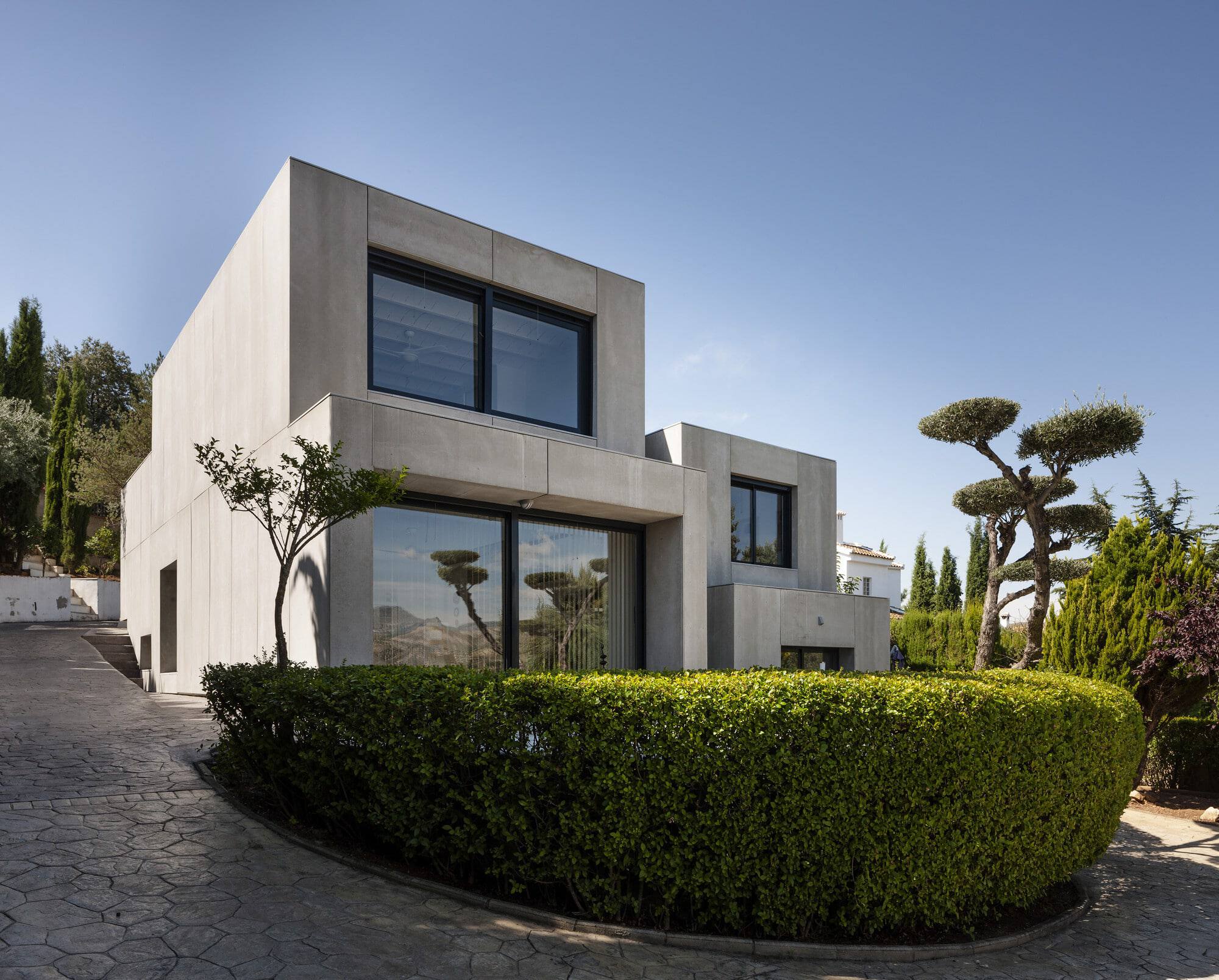 Contemporary modern house with minimalist concrete architecture, large glass windows, and landscaped garden, showcasing innovative residential design.