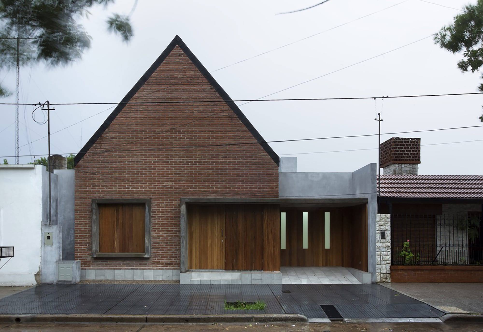 Contemporary residential house with modern brick and wood facade, minimalist design, and unique roofline blending traditional and modern architectural styles.