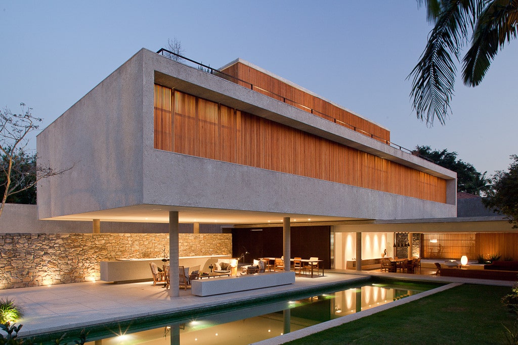 Contemporary modern house with minimalist architecture, featuring expansive glass windows, concrete and wood elements, and a sleek outdoor pool area. Perfect example of innovative residential design.