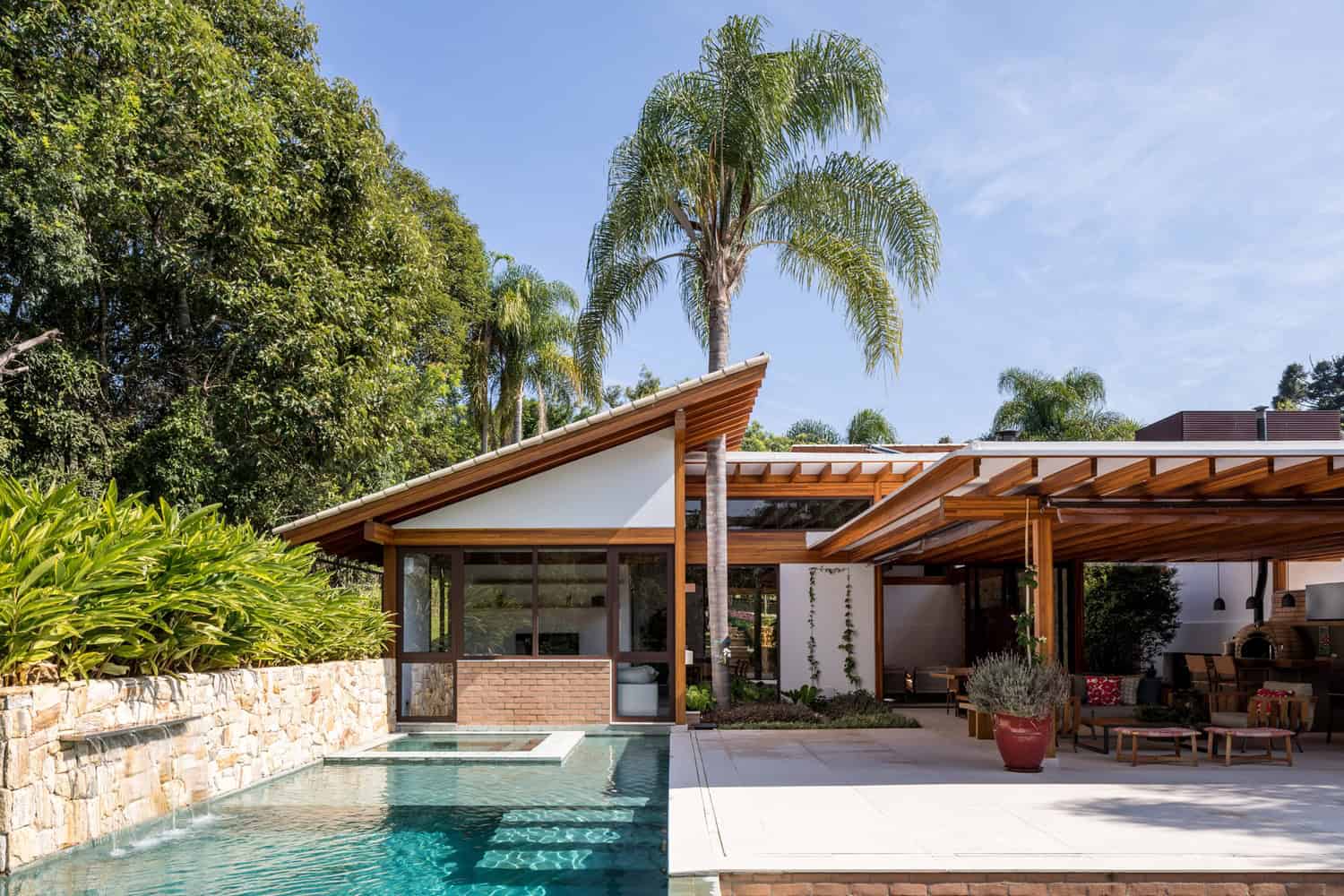 Modern residential house with a pool, featuring contemporary architecture, wooden accents, and lush landscaping in a tropical setting.