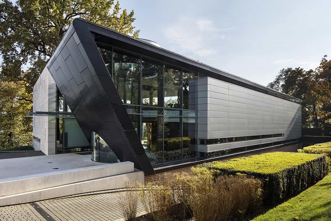 Futuristic modern architecture building with sleek black and white exterior design, expansive glass windows, and lush landscaped surroundings, showcasing innovative architectural art and contemporary design.