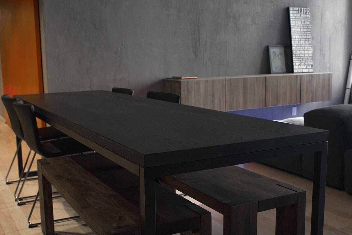 Sleek modern black dining table with matching chairs and wooden benches in contemporary interior design.