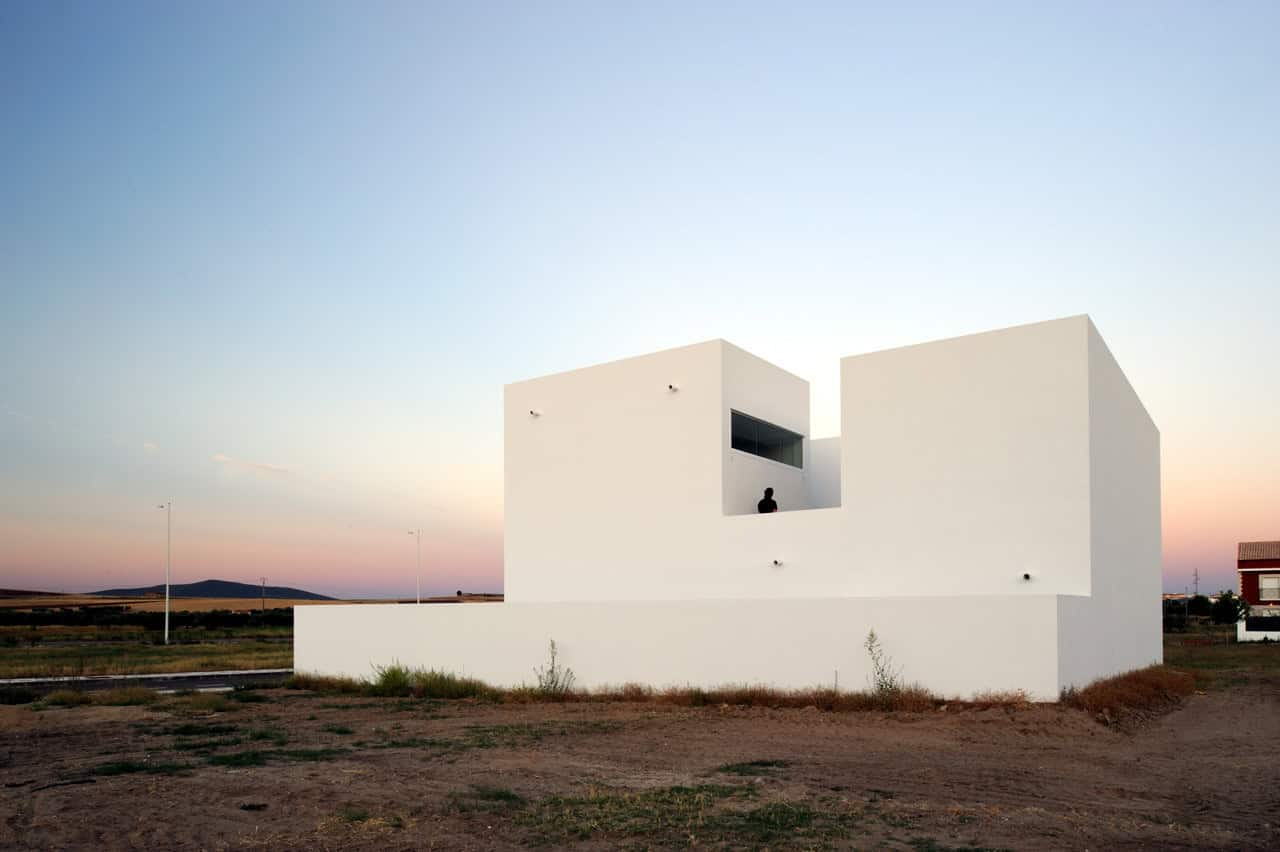 Modern minimalist white house with geometric design and clean lines, set in a rural landscape during sunset. Perfect example of contemporary architecture art and innovative architectural design.