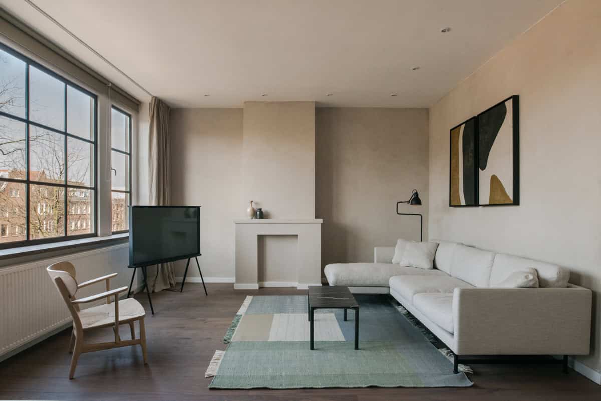 Modern minimalist living room with neutral tones, large windows, abstract artwork, and contemporary furniture for stylish architectural interior design.