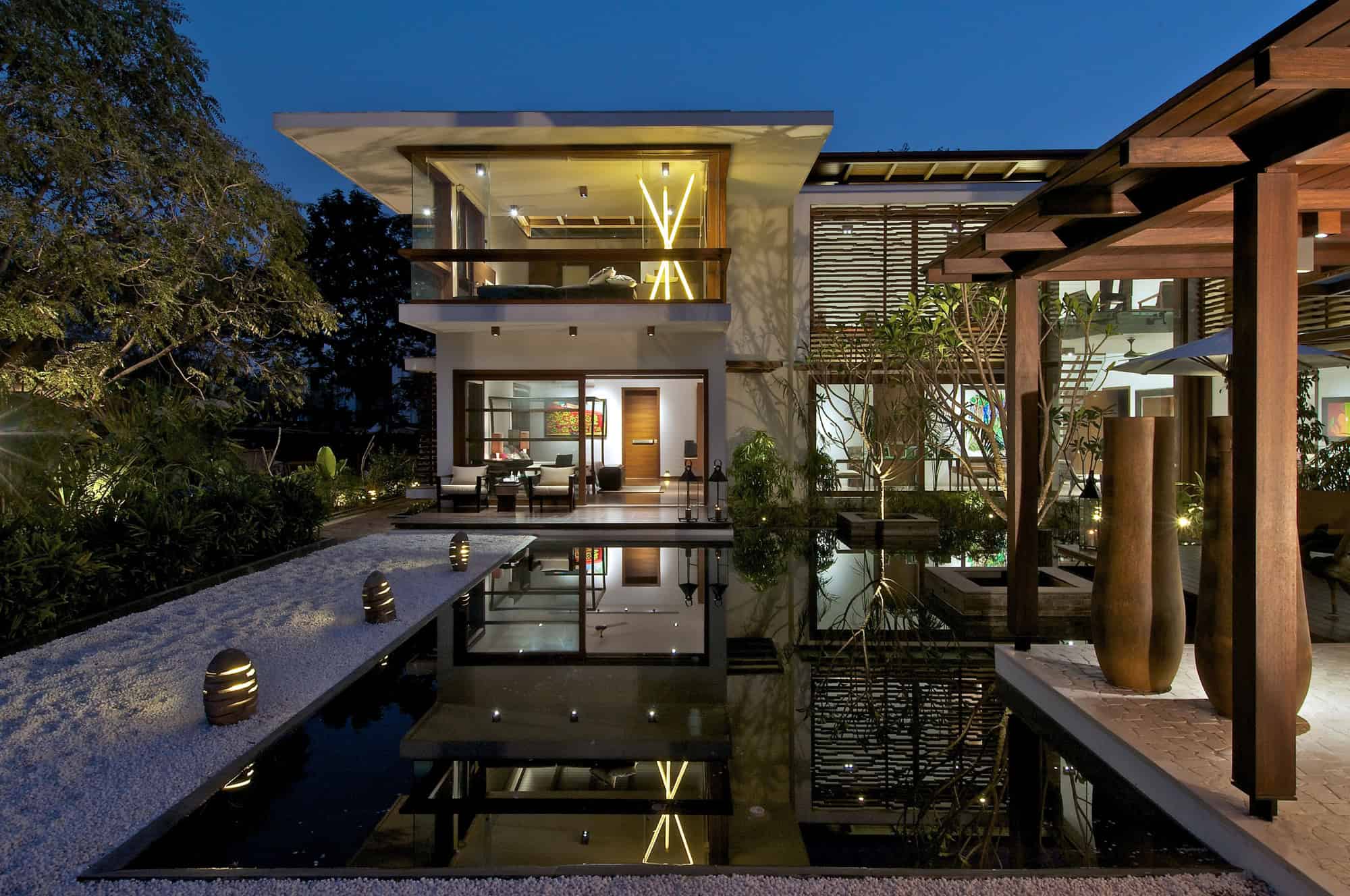Modern contemporary house with elegant design, large glass windows, outdoor water feature, and lush greenery, showcasing stylish architecture and luxurious outdoor living spaces.