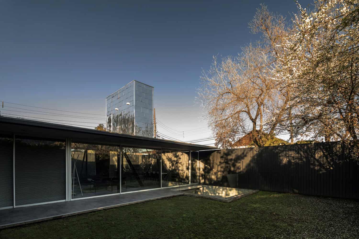 Contemporary modern house with sleek glass facade and minimalist design, surrounded by trees and outdoor space, showcasing innovative architecture and stylish home design.