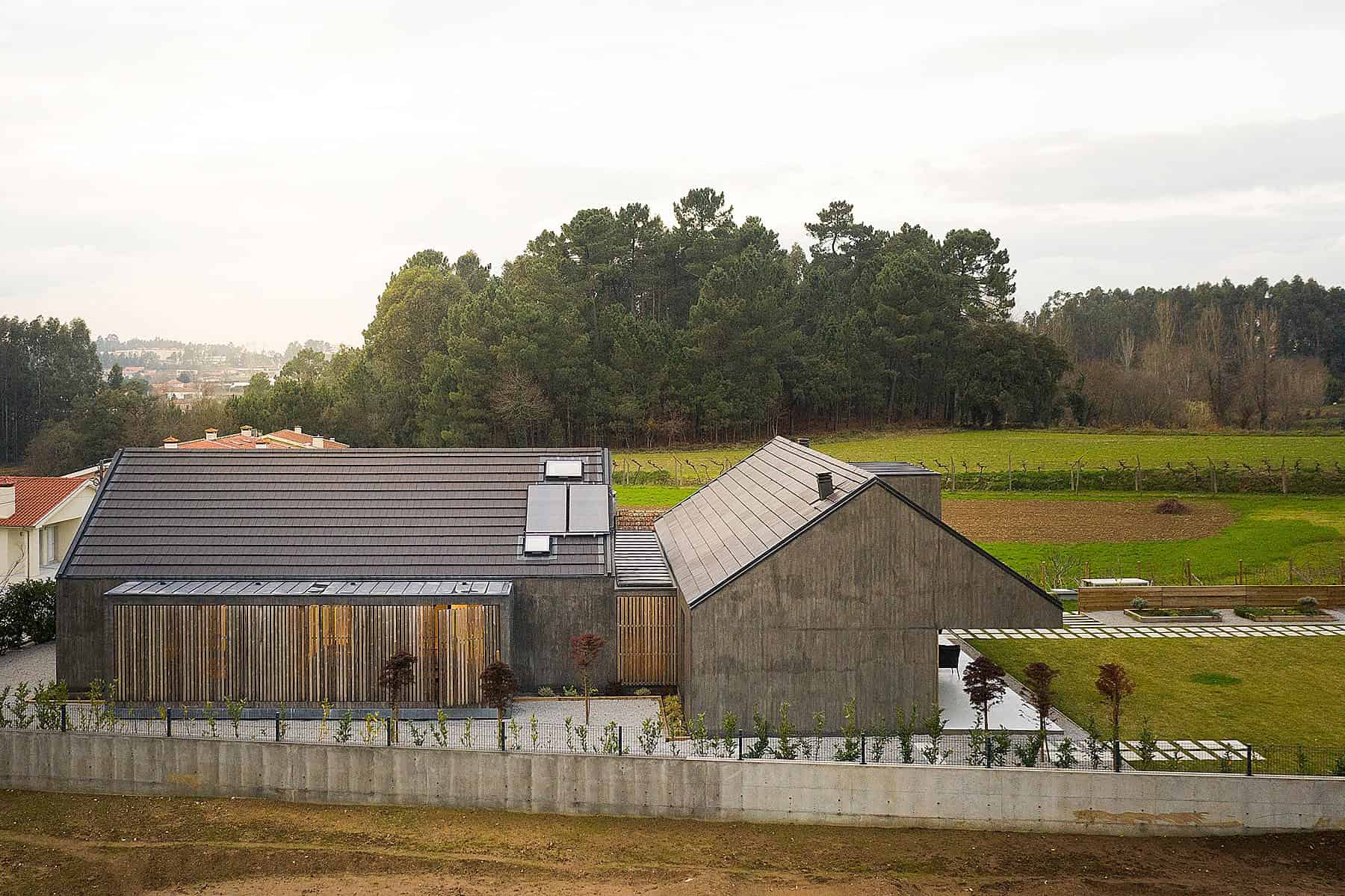 Contemporary modern house with sleek metal roof and wood accents, surrounded by greenery and open fields, showcasing innovative architecture, stylish design, and sustainable building materials.