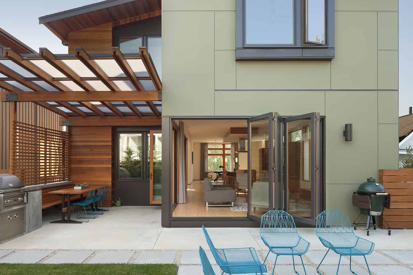 Modern contemporary house with a spacious outdoor patio featuring wooden accents, glass doors, outdoor seating, and a green exterior wall, perfect for stylish outdoor living and entertaining.