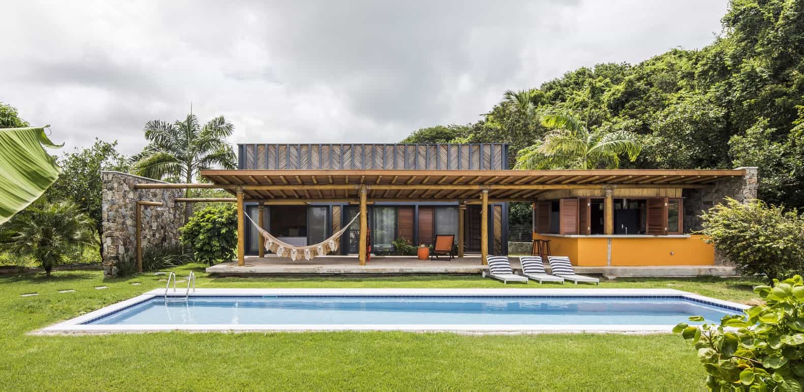 Modern tropical villa with a private pool, lush greenery, and unique architectural design featuring natural stone and wooden elements. Perfect for luxury outdoor living and relaxation.