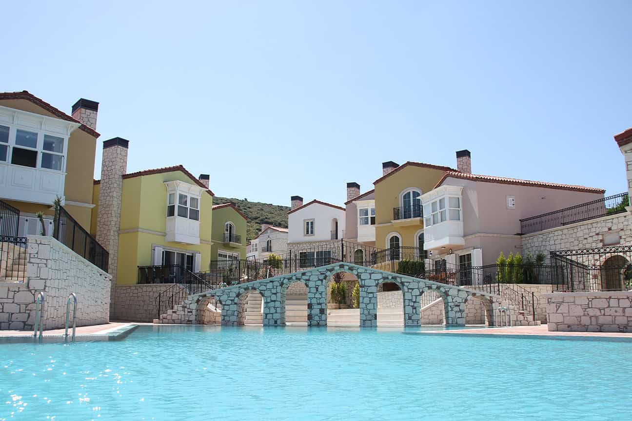 Modern Mediterranean hillside villas with luxury swimming pool and stone accents, showcasing stunning architecture and outdoor living in a scenic mountain setting.