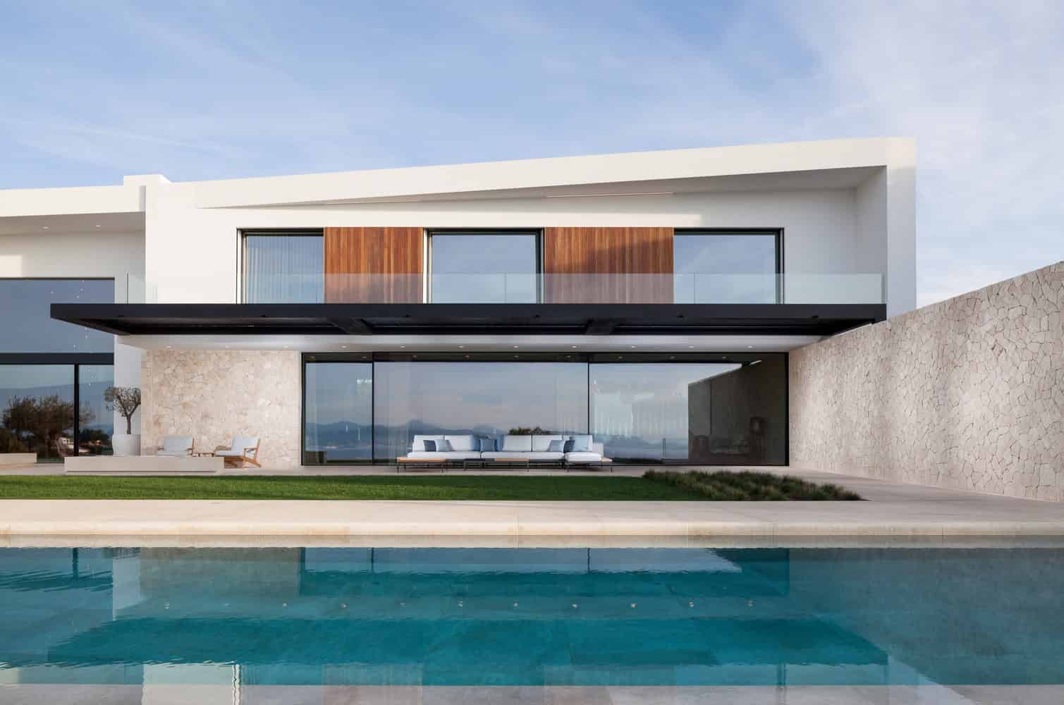 Modern luxury house with sleek minimalist architecture featuring large glass windows and a swimming pool, emphasizing contemporary design and outdoor living spaces.