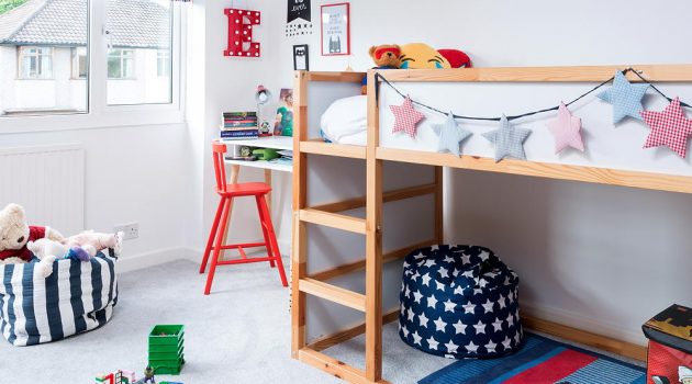 Children's room with star shape bunting strung along wooden bunk bed with red painted chair by desk and blue and red striped Roman blinds