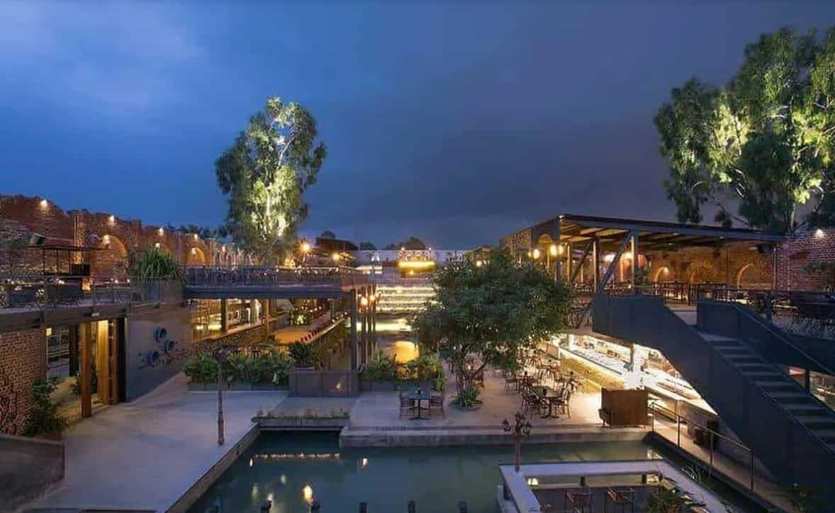 Modern urban terrace with outdoor seating, lighting, and greenery under night sky, showcasing contemporary architecture and innovative design elements for stylish outdoor living.
