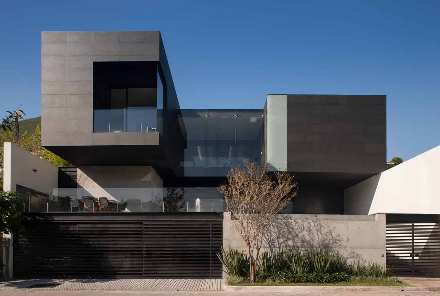 Contemporary modern house with sleek black and gray exterior, large glass windows, minimalist architecture, and landscaped garden, showcasing innovative residential design.