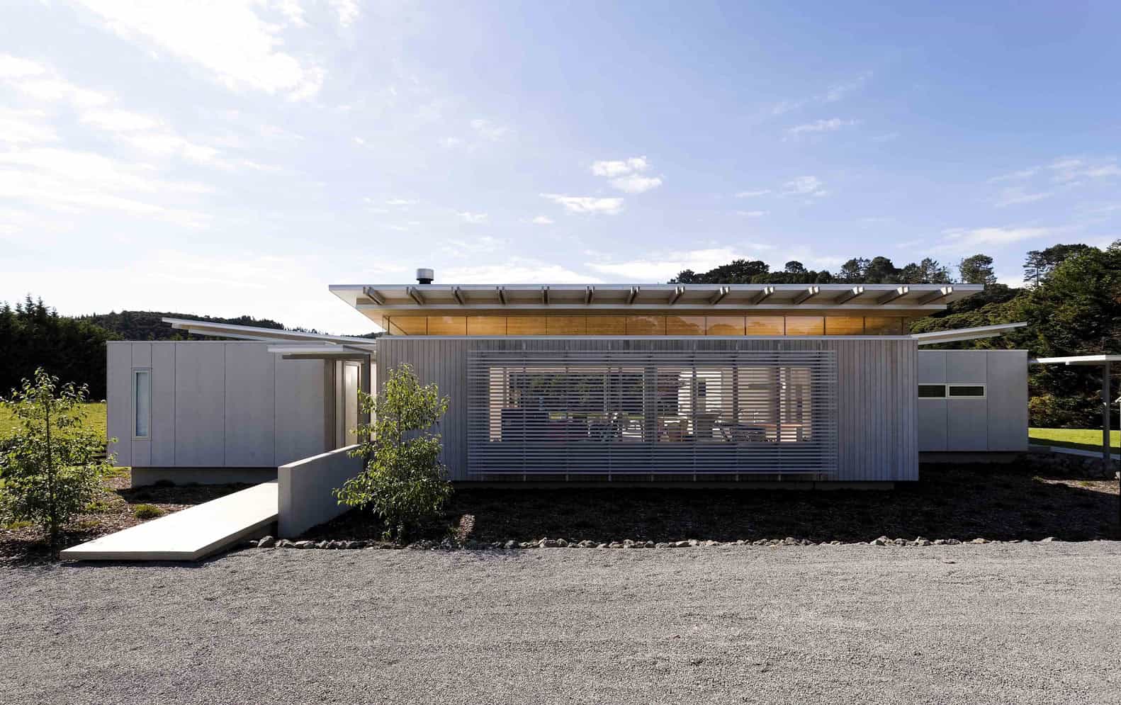 Modern minimalist house made of metal and glass with sleek design and contemporary architecture, featuring unique roofline and large windows set in a scenic natural landscape.