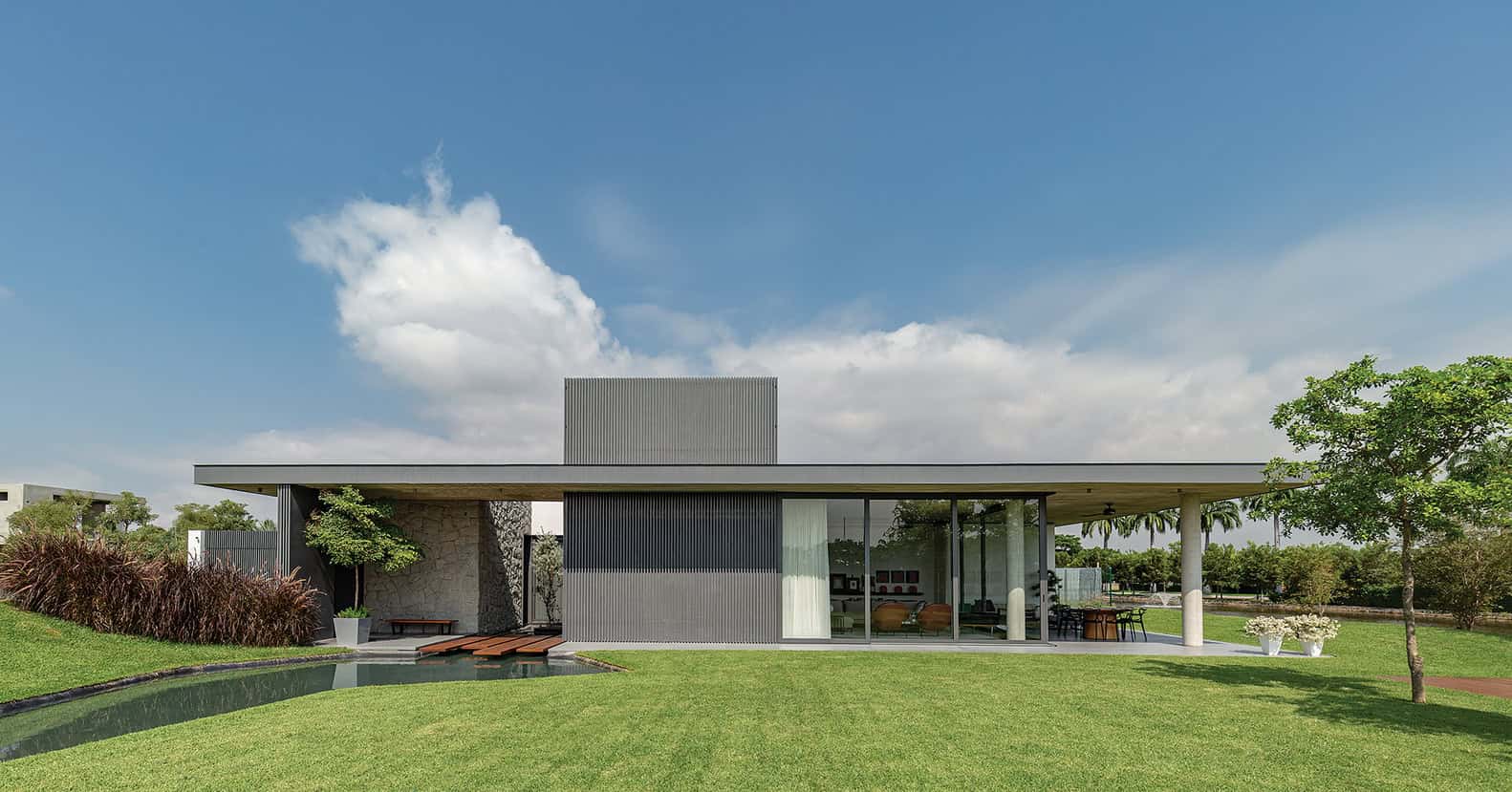 Modern minimalist house with sleek design, large glass windows, and lush green landscaping, showcasing contemporary architecture and outdoor living space.