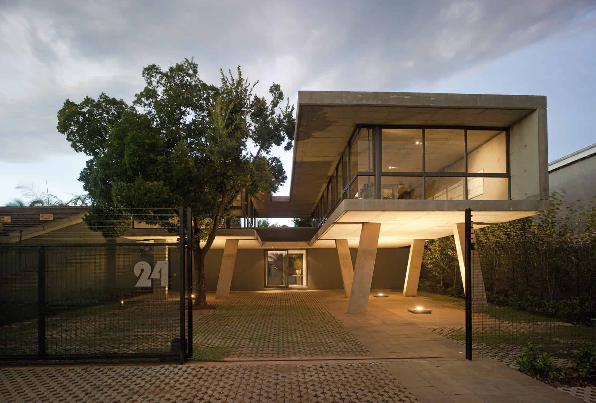 Contemporary modern concrete house with large glass windows and unique architectural design, illuminated at dusk, showcasing innovative architecture and modern home design.