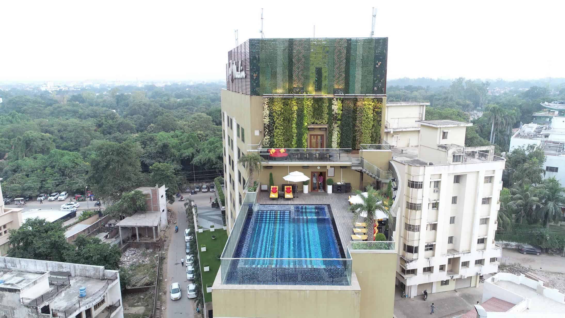 Luxurious rooftop swimming pool with stylish outdoor lounge area, surrounded by modern urban architecture and lush greenery, offering a relaxing retreat in the city.