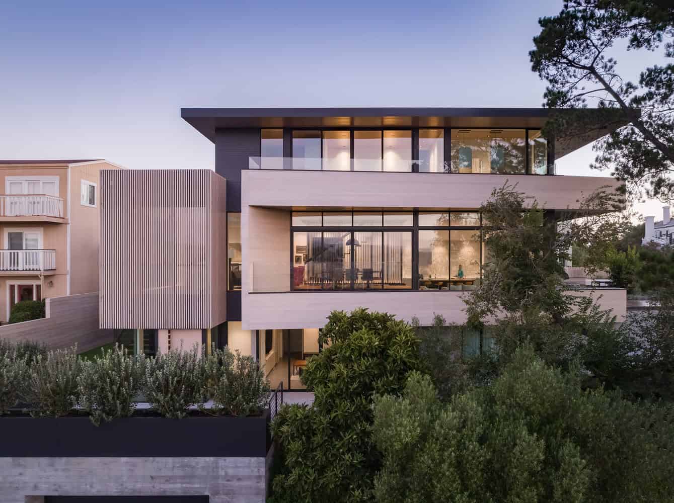 Modern luxury house exterior with sleek architectural design, expansive glass windows, and contemporary style, surrounded by greenery.