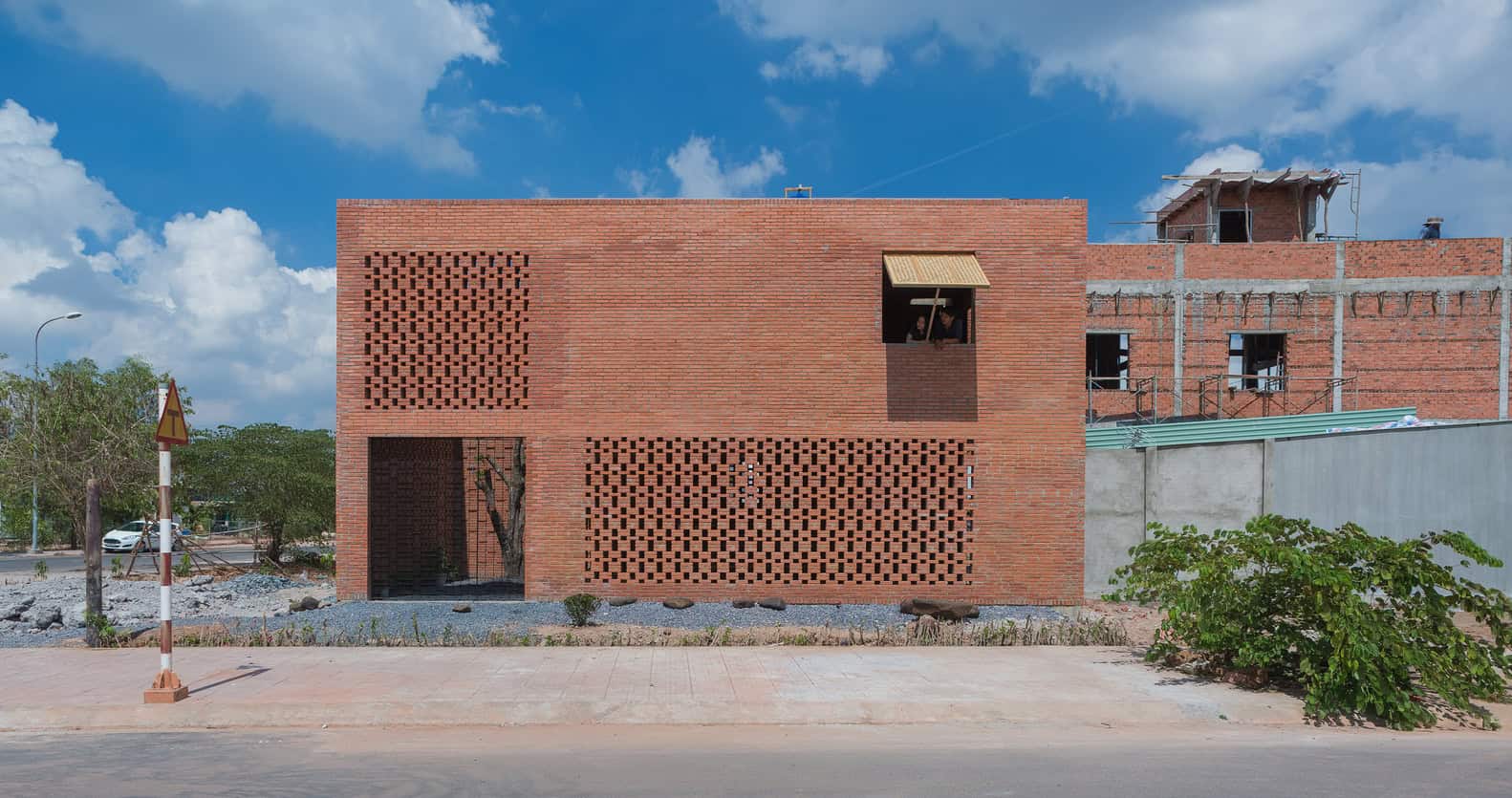 Modern brick building under construction showcasing innovative architectural design and brickwork patterns, set against a vibrant blue sky.