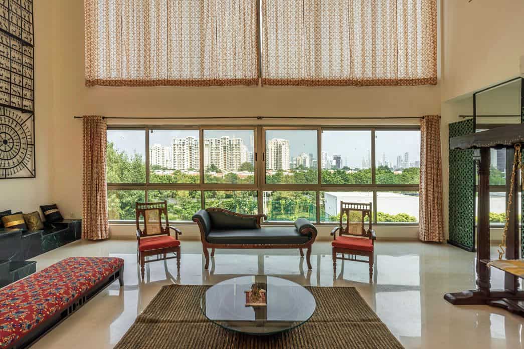 Modern living room with large windows, elegant antique furniture, and a city view, combining contemporary design with classic architectural elements for a stylish interior.